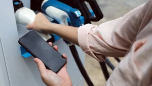 Driver holding smartphone to pay at a public EV charge point without a fuel card